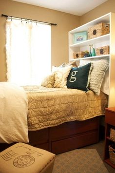 a small bedroom with a bed, dresser and shelves in the corner that have baskets on them