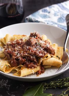 pasta with meat sauce and parmesan cheese in a white bowl on a table