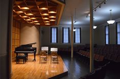 an empty stage with chairs and a piano in the foreground is lit by lights