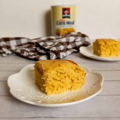 a piece of cornbread on a plate next to a can of cornmeal