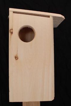 a wooden birdhouse with a hole in the side for birds to peck at, on a black background