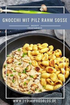 a pan filled with pasta and mushrooms on top of a table next to some vegetables