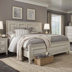 a white bed sitting in a bedroom next to two lamps and a rug on top of a wooden floor