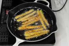 fried food being cooked in a skillet on top of a stove with a computer keyboard next to it