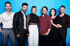 a group of people standing next to each other in front of a blue background,