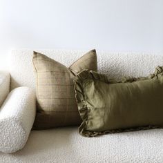 two pillows sitting on top of a white couch next to a pillow with ruffled edges