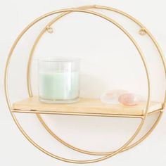 a candle is sitting on a shelf in front of a circular wall hanging with gold rings