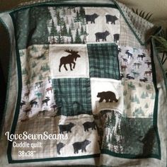 a quilted blanket with bears and moose on it, sitting on top of a table