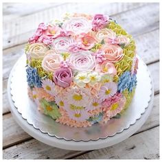 there is a cake decorated with flowers on top of a plate and sitting on a wooden table