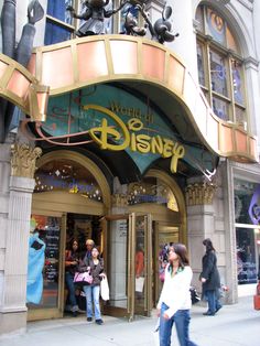 people are walking in front of the entrance to disney's beauty and the beast