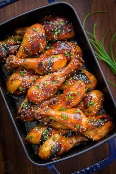 chicken wings with sesame seeds and seasoning in a baking dish on a wooden table