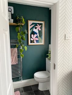 a bathroom with green walls and white tile flooring is pictured from the doorway to the toilet