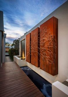 a large metal artwork hanging on the side of a wall next to a wooden deck