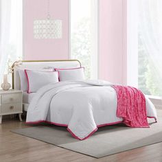 a white bed with pink trim and pillows in a room that is painted bright pink