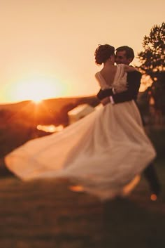 a bride and groom dancing in front of the sun