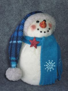 a stuffed snowman wearing a blue scarf and hat with a star on it's forehead