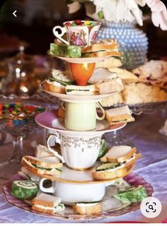 a stack of tea cups and sandwiches on a table