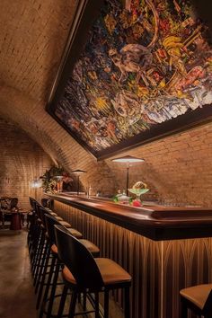 a bar with several stools in front of a painting on the wall above it