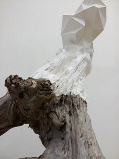 a piece of driftwood with an origami sculpture on top