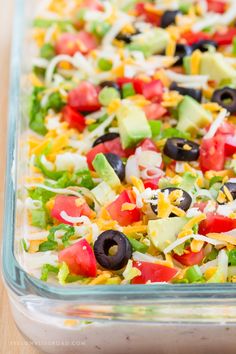 a glass dish filled with mexican salad and tortilla chips