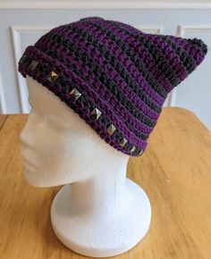 a crocheted hat with rivets is on a mannequin head