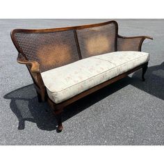 a wooden bench sitting on top of a parking lot next to a cement ground with no people