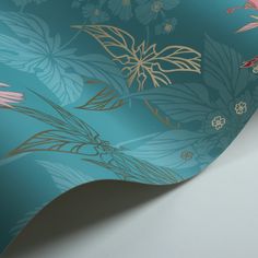 the wallpaper is blue and has pink flowers on it with gold foiled leaves