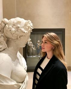 a woman standing next to a white statue