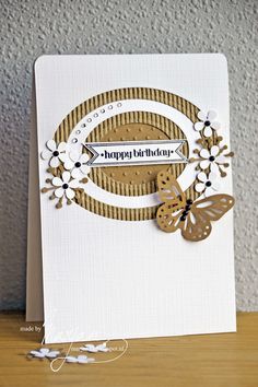 a close up of a birthday card on a wooden table with paper flowers and butterflies