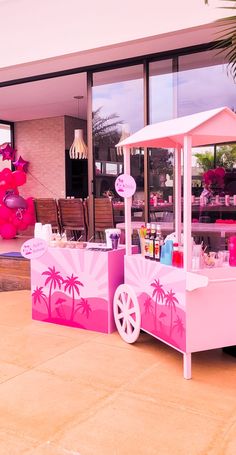 a pink ice cream cart with palm trees painted on the side and windows behind it