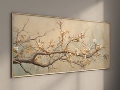 a painting hanging on the wall with white flowers and leaves in it's branches