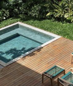 an above ground pool surrounded by wooden decking and lawn chairs with green plants in the background