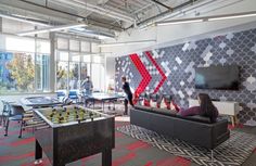 two people are playing foo - pong in an office with large windows and colorful wallpaper