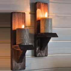 two candles are lit on the wooden wall sconces, one is made out of wood