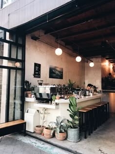 the inside of a coffee shop with potted plants