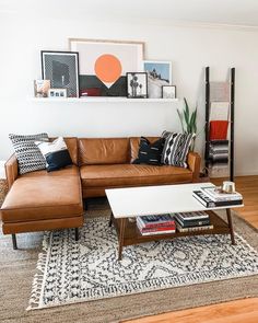 a living room with brown leather couches and pictures on the wall above it's coffee table