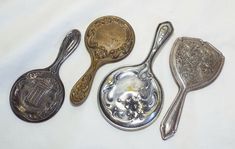 four antique spoons are lined up next to each other on a white tablecloth