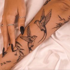 a woman's arm with tattoos on it and birds flying around the wrist area