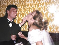 a young man and woman feeding each other cake at their wedding reception in an old photo