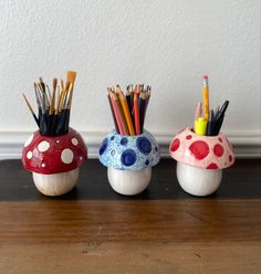 three ceramic mushrooms with pencils and markers in them