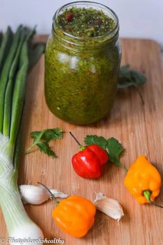 some vegetables are sitting on a cutting board next to a jar of pesto sauce