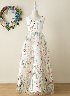 a dress on a mannequin next to a wreath and wall hanging with flowers