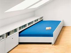 there is a blue bed in the corner of this room with white walls and wooden flooring