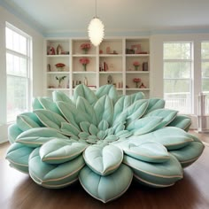 a large blue flower sitting on top of a wooden floor in front of a bookshelf