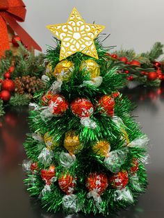 a christmas tree made out of candy wrapped in tinsel and decorated with gold star