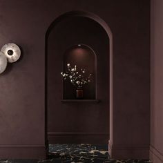 a hallway with purple walls and marble flooring, two vases on the wall