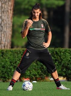 a man standing on top of a lush green field next to a soccer ball