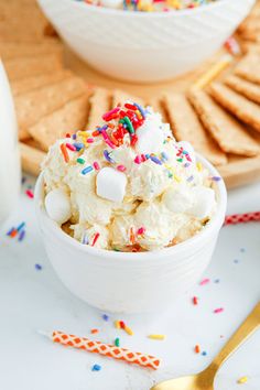 a white bowl filled with ice cream and sprinkles next to crackers