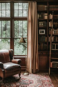 a leather chair sitting in front of a window next to a book shelf filled with books