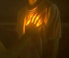 a man is holding his hands up in the dark with light coming from behind him